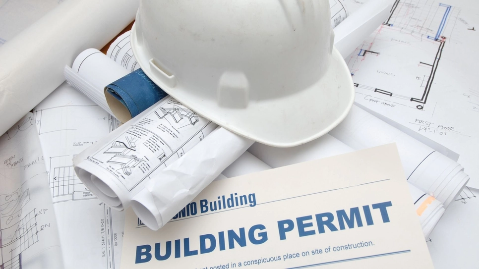 Building permit and blueprint documents with a white helmet on top.