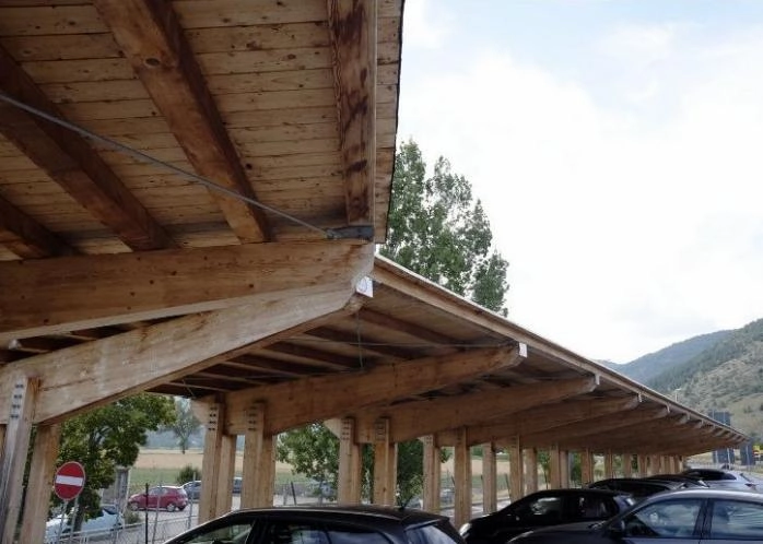 Wooden carport with cars underneath.