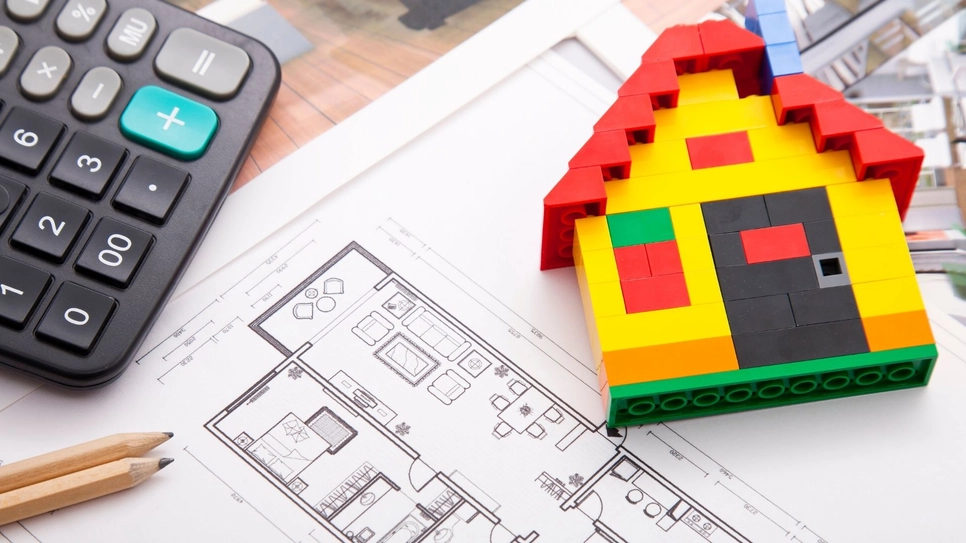 House plan with a pencil and a miniature lego house on it.