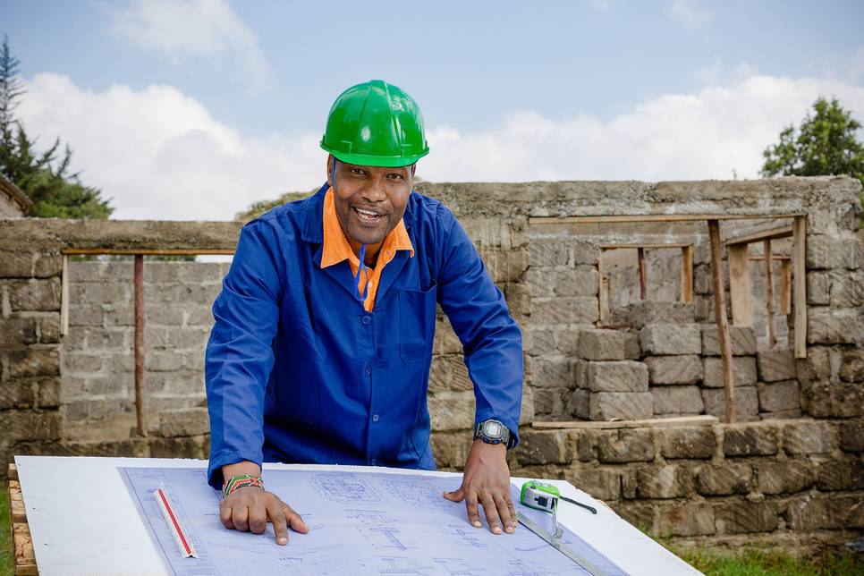 Happy black professional builder with a plan in front of him.