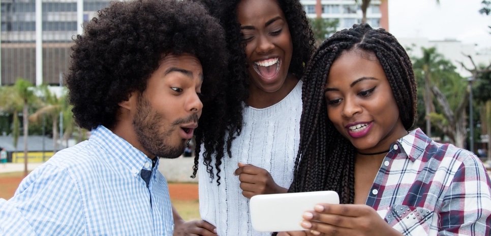 Three Africans watching the mobile phone screen.