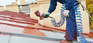 painter paints a metal roof