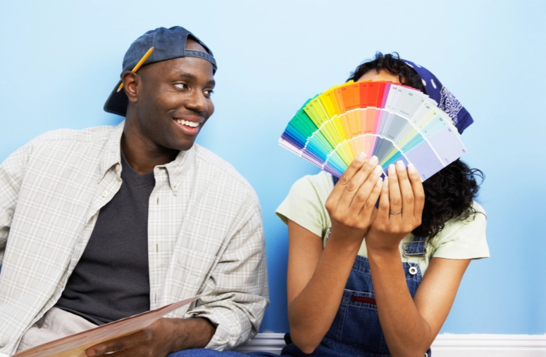 An African couple choosing paint for their home. Woman has face covered with a colour palette.