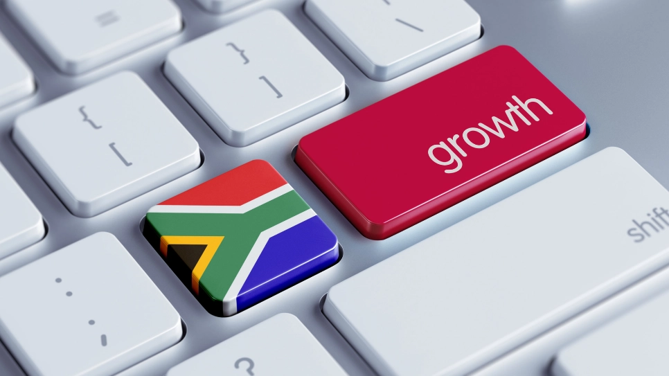 A computer keyboard with two standout keys; one key features the South African flag, symbolizing national identity, and the adjacent red key is labeled growth,representing economic or personal development.