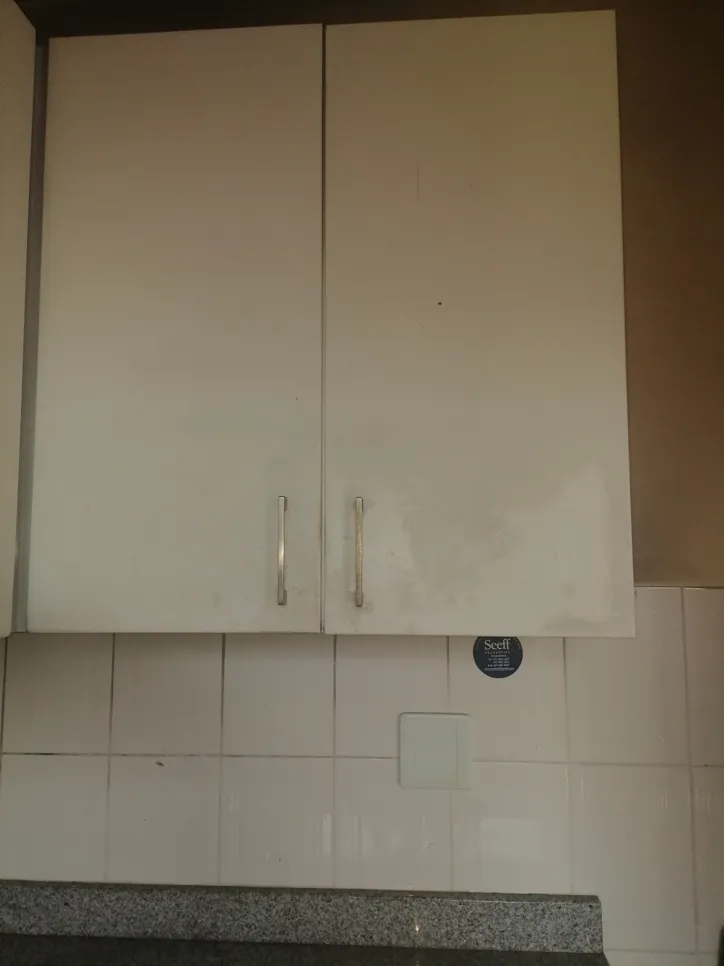 White kitchen cabinets with visible dirt and grime on the surface, needing cleaning.