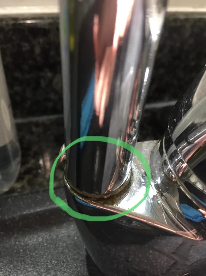 Close-up of a faucet base with visible mineral buildup indicating a potential leak issue.