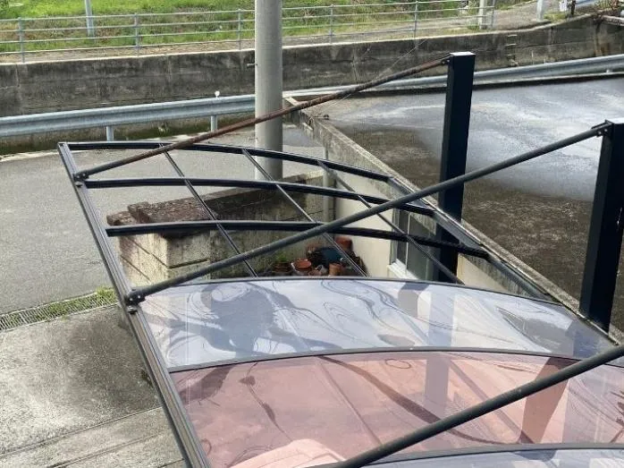 Half of carport covered by a plastic material, the other half without a cover.