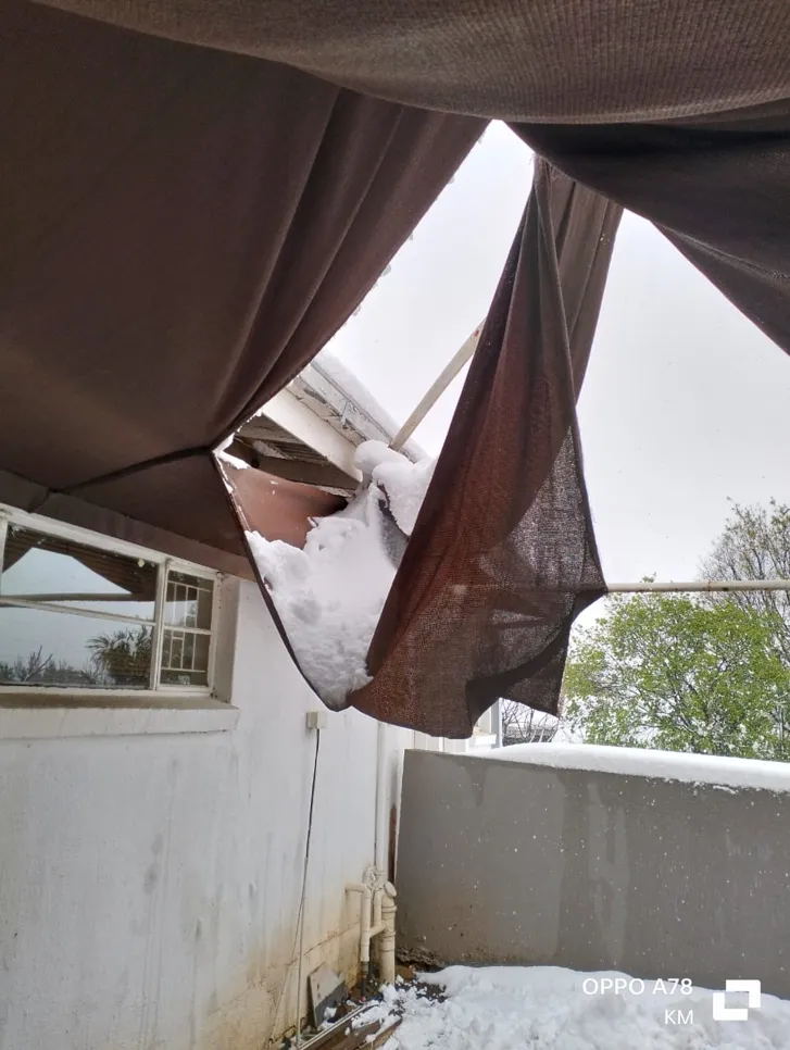 Outdoor awning torn by accumulated snow, causing fabric sagging and structural strain.