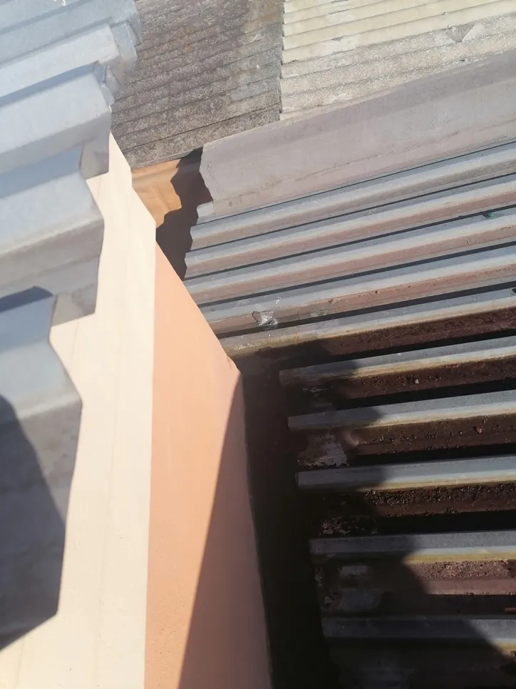 Close-up of a corrugated metal roof junction showing potential water leakage points.