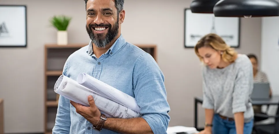 architect holding the blueprints, smiling