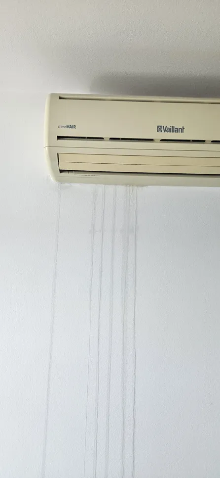 Air conditioner with visible water stains on the wall, indicating a leakage issue.