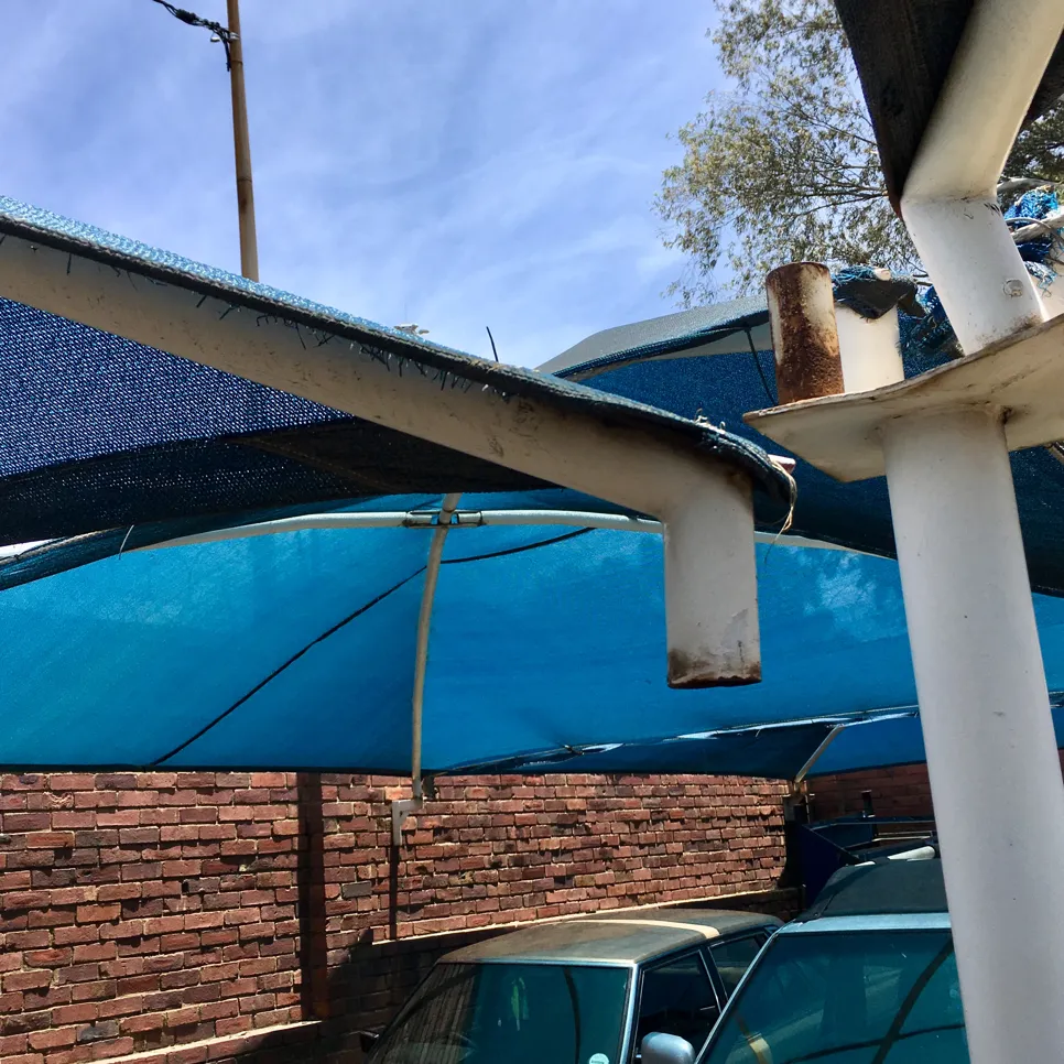 A blue carport shade with rusted metal frame showing signs of wear and tear.