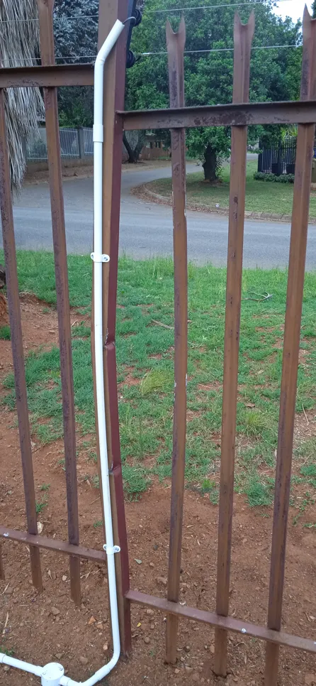 Bent metal fence with attached conduit pipe (13660) Bent metal fence section with a white conduit pipe attached, highlighting damage and repair needs.