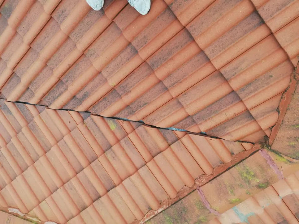 Cracked clay roof tiles with visible damage, highlighting potential leakage issues.