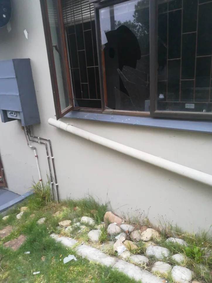 Shattered window with broken glass in a residential setting, indicating potential security concerns.