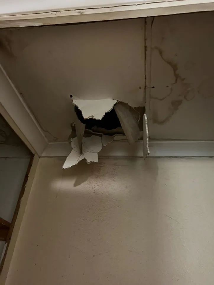 Damaged ceiling with a visible hole and water stains, indicating possible water leakage.
