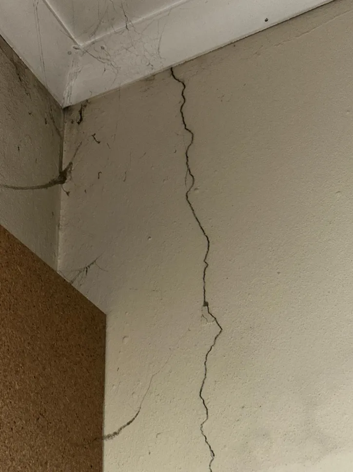 A visible crack runs down a wall corner near the ceiling, indicating potential structural issues.
