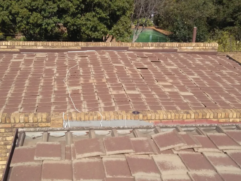 Roof with misaligned and damaged tiles showing visible gaps, indicating potential structural issues.