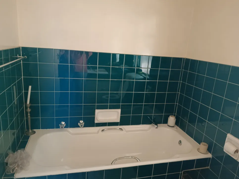 A bathroom featuring a white bathtub surrounded by blue tiles, showcasing a classic design.