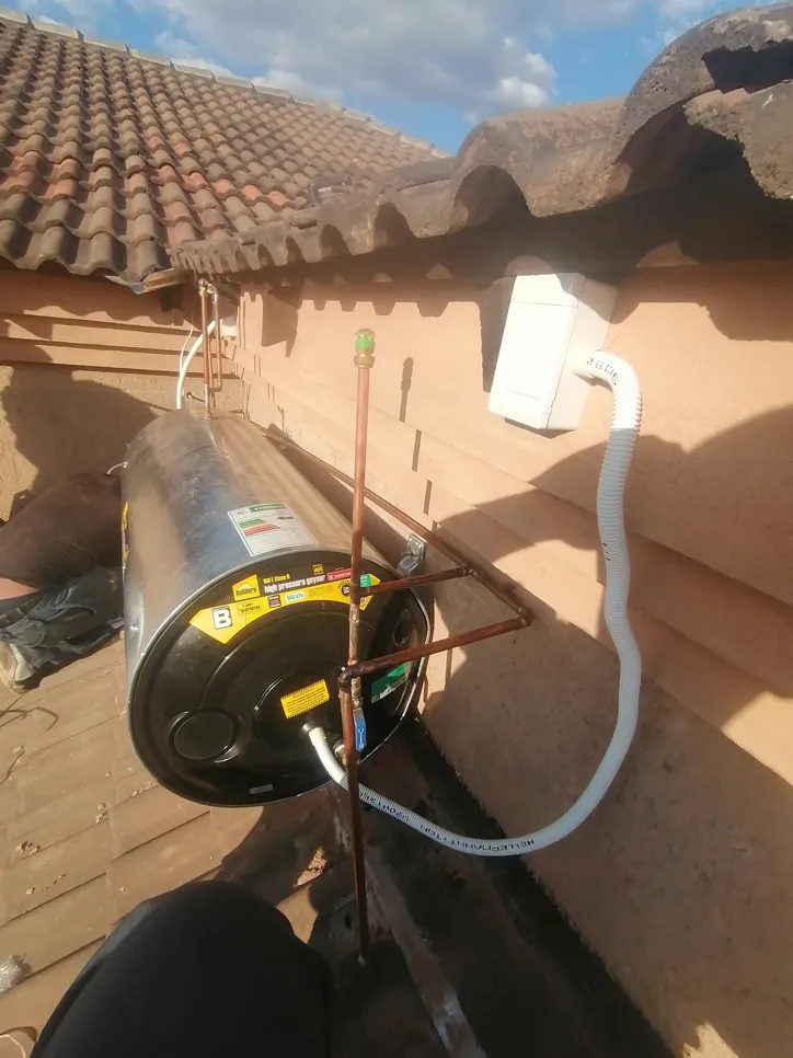 Solar water heater installation on rooftop (27147) Rooftop solar water heater mounted near tile roof with connected piping and electrical components.