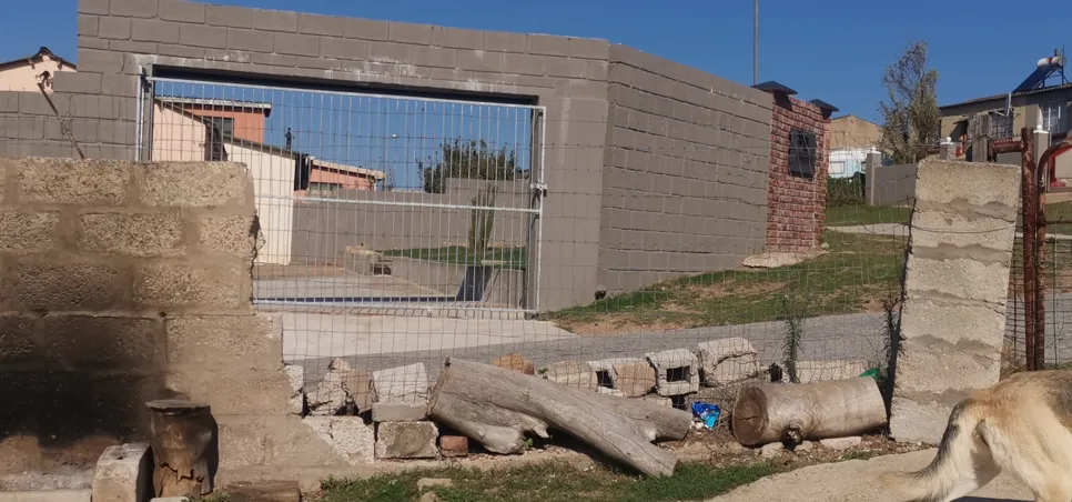 Damaged brick wall and fence Damaged brick wall and wire fence with fallen logs, indicating a need for structural repair.
