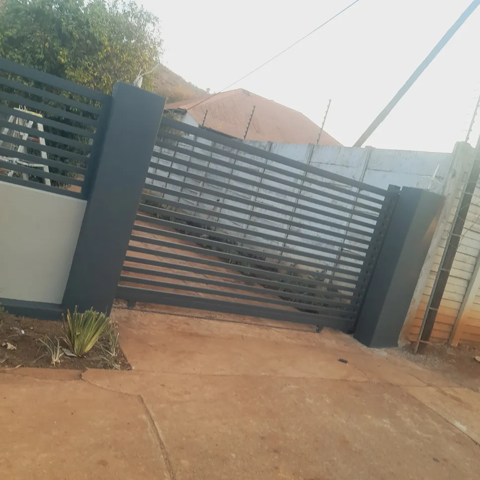 A sleek, horizontal slat metal gate installed at a residential driveway entrance, providing security and style.
