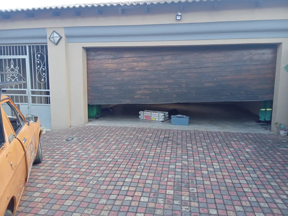 Garage door misalignment causing uneven opening, revealing tools and equipment inside the garage.