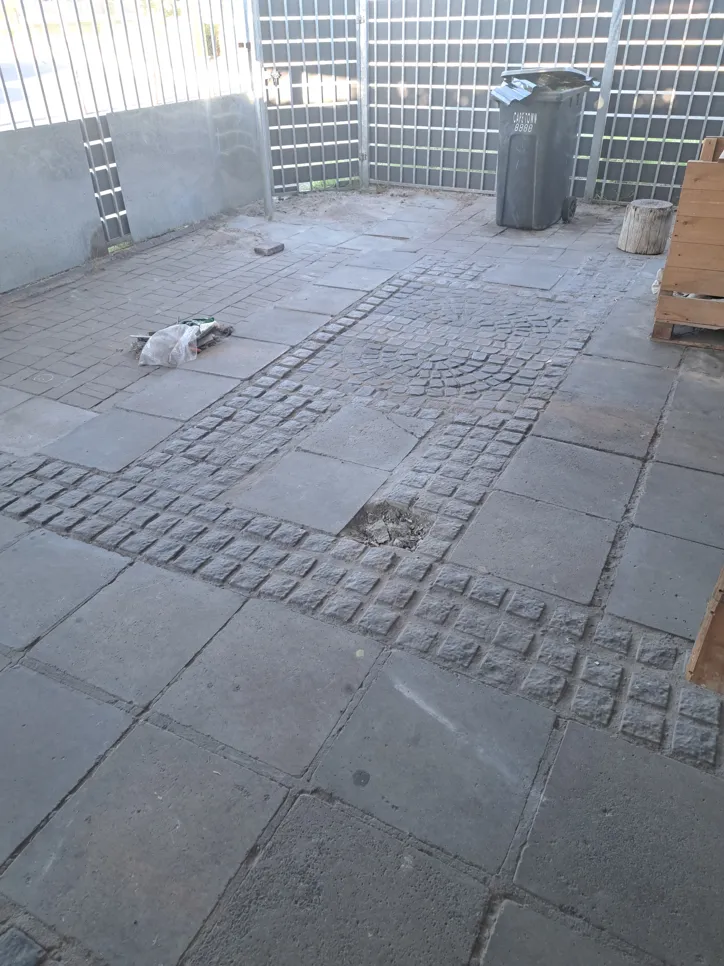 Outdoor patio with uneven and damaged paving stones, showing a need for repair or replacement.