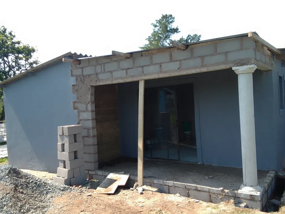 Partially constructed house with exposed bricks and unfinished porch area.