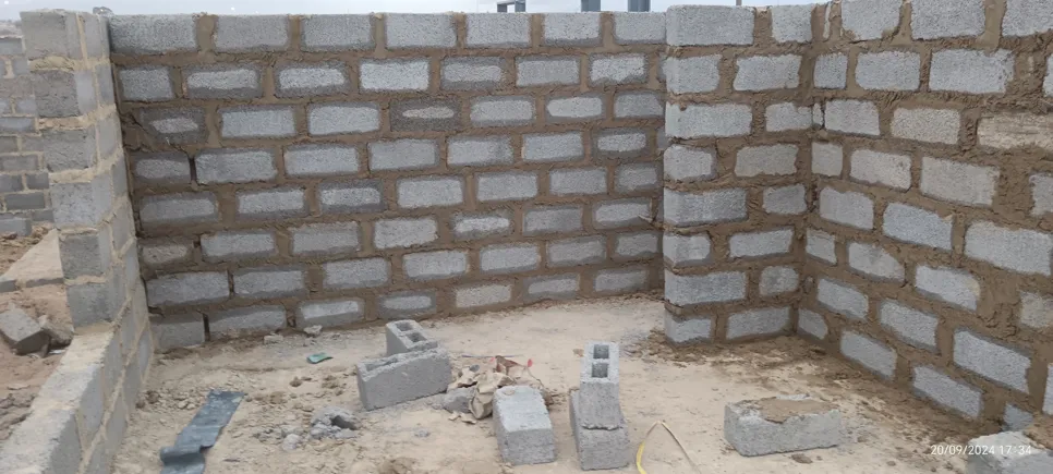 Partially constructed brick walls with visible mortar, showing early stages of building structure.