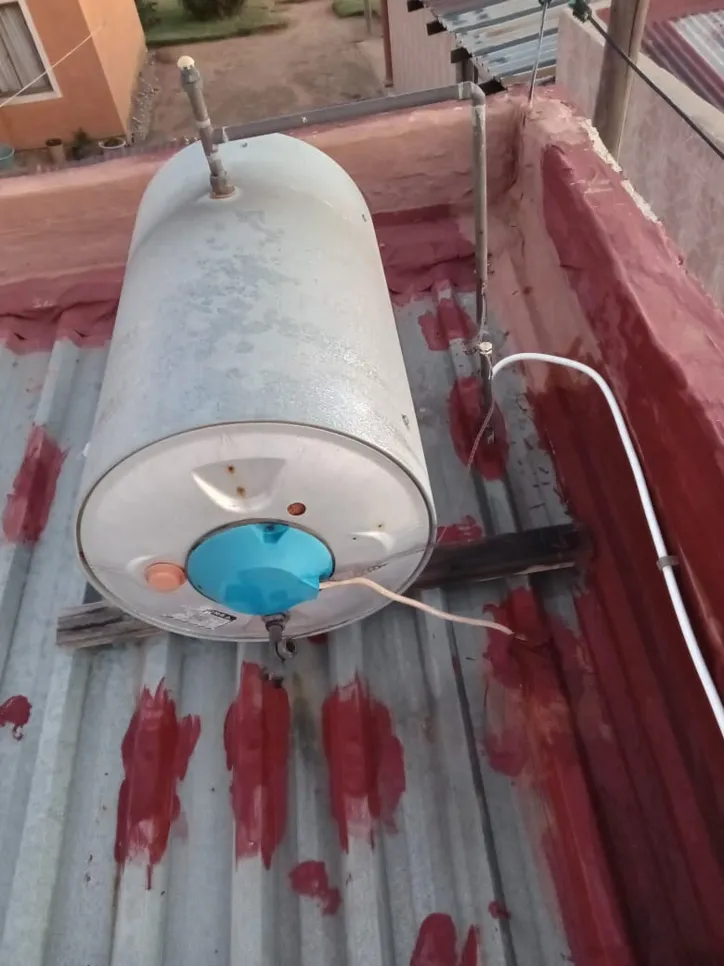 Rooftop water heater installation (20398) Rooftop water heater installed on metal sheets with visible piping and wiring connections.