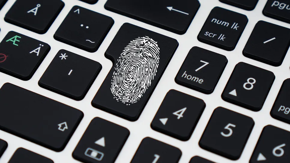 A close-up of a computer keyboard shows a fingerprint icon on the enter key, symbolizing biometric login and digital security.