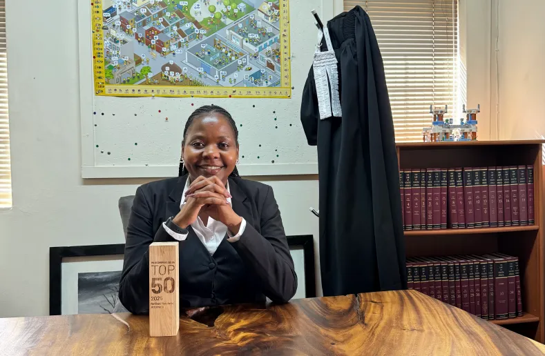 Pretoria attorney Refilwe Matsimbi at her desk, framed by legal volumes and her professional robes, celebrating her 2025 induction into the elite Procompare.co.za TOP 50 circle of excellence.