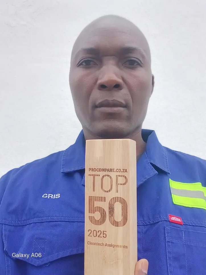 Cris from Cleantech Assignments stands with quiet confidence in his professional blue gear, holding the wooden Procompare.co.za TOP 50 trophy that cements his business's reputation as one of South Africa’s elite service providers for 2025.